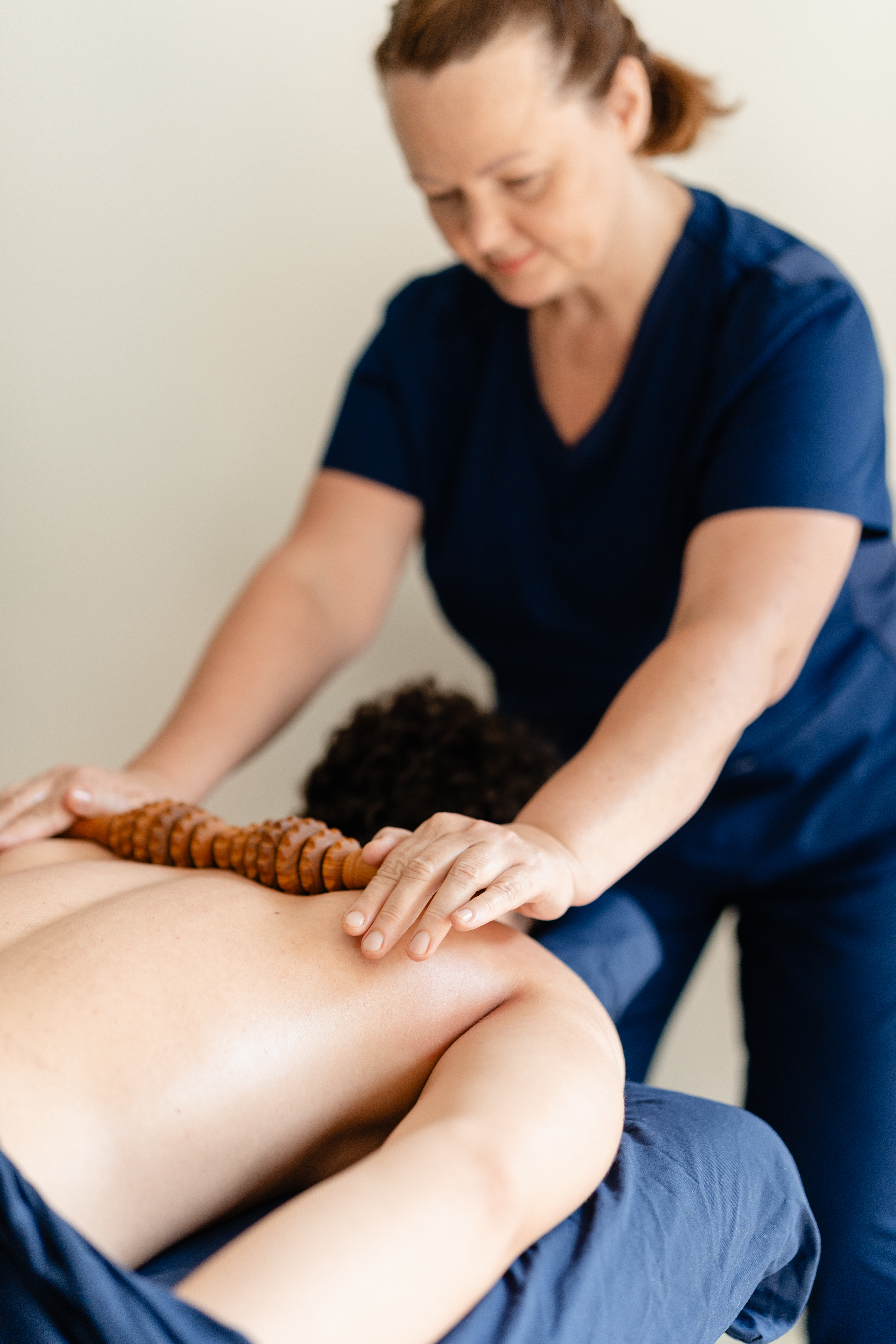 Inna Cherevatenko utilise un rouleau de massage en bois sur le dos d’une cliente.